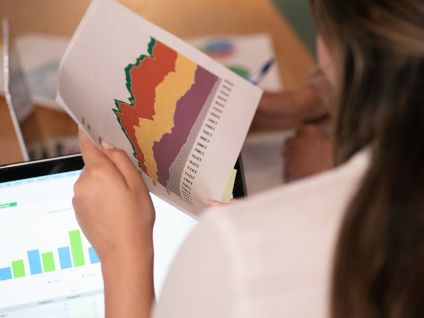 Close-up of a woman analyzing colorful charts and graphs in an office setting.